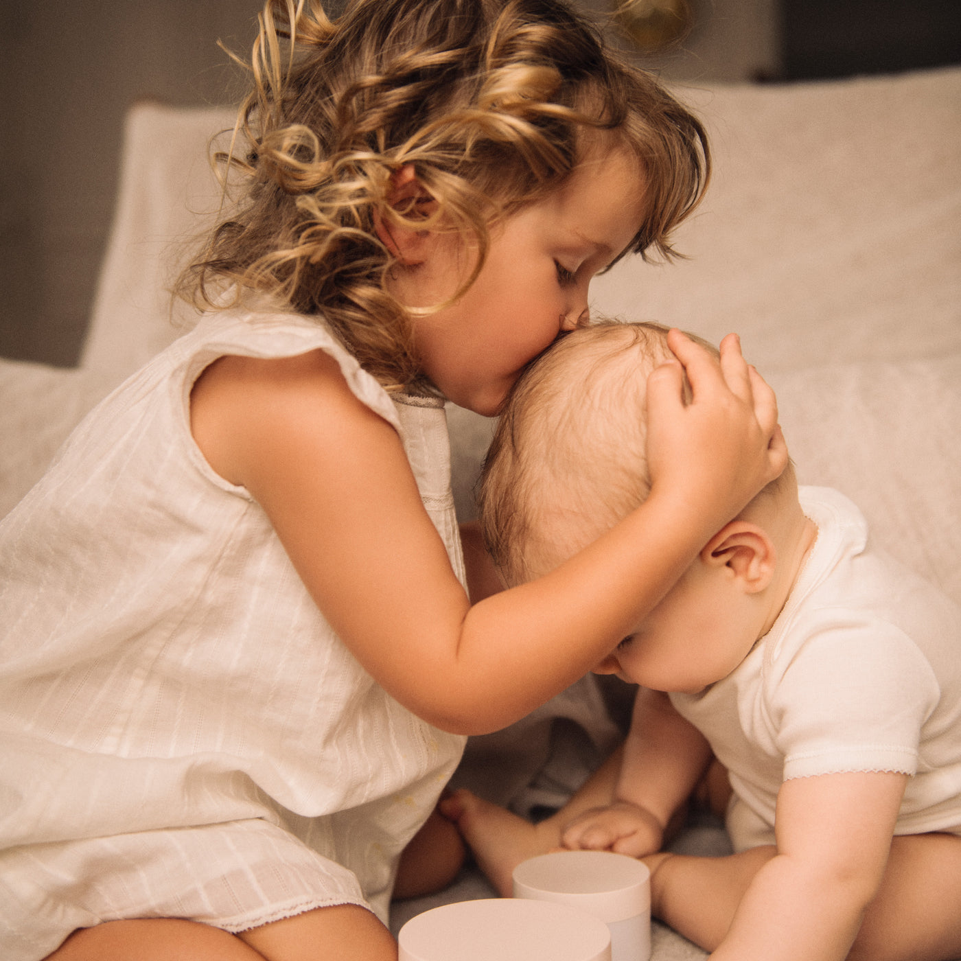 Bonpoint young girl kissing a baby's head
