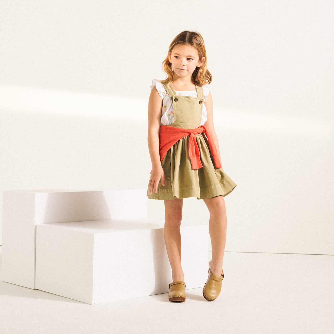 Girl in green toned overall dress from Bonpoint Spring Summer 2022 Collection