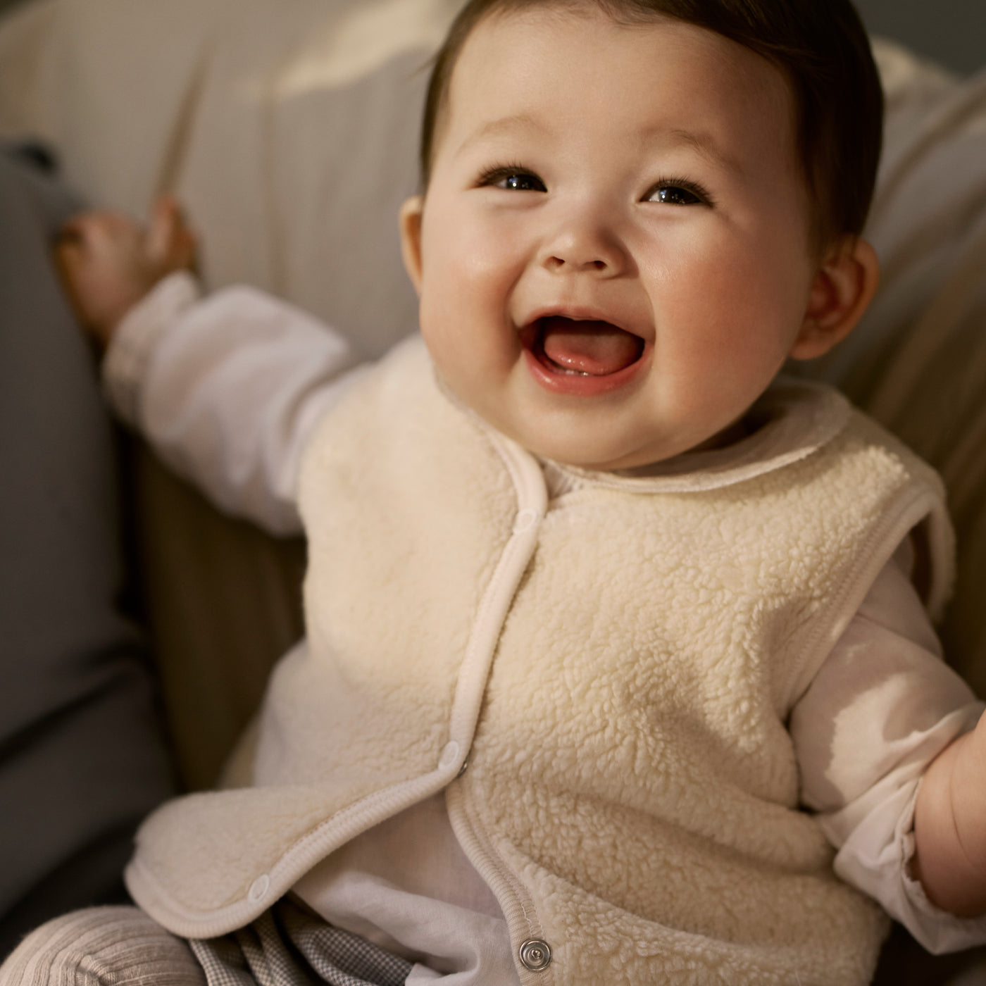 Bonpoint baby laughing in furry cream vest