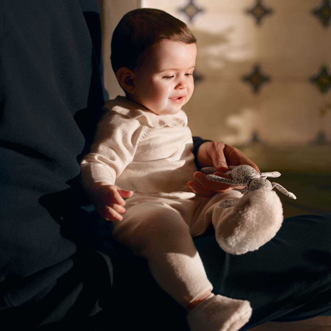 Bonpoint baby being held with floral bunny toy