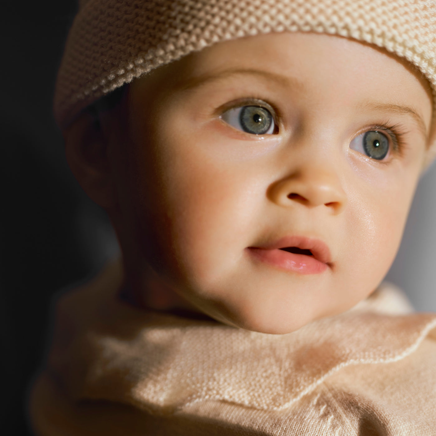 Bonpoint baby close up on facial features wearing a neutral beanie