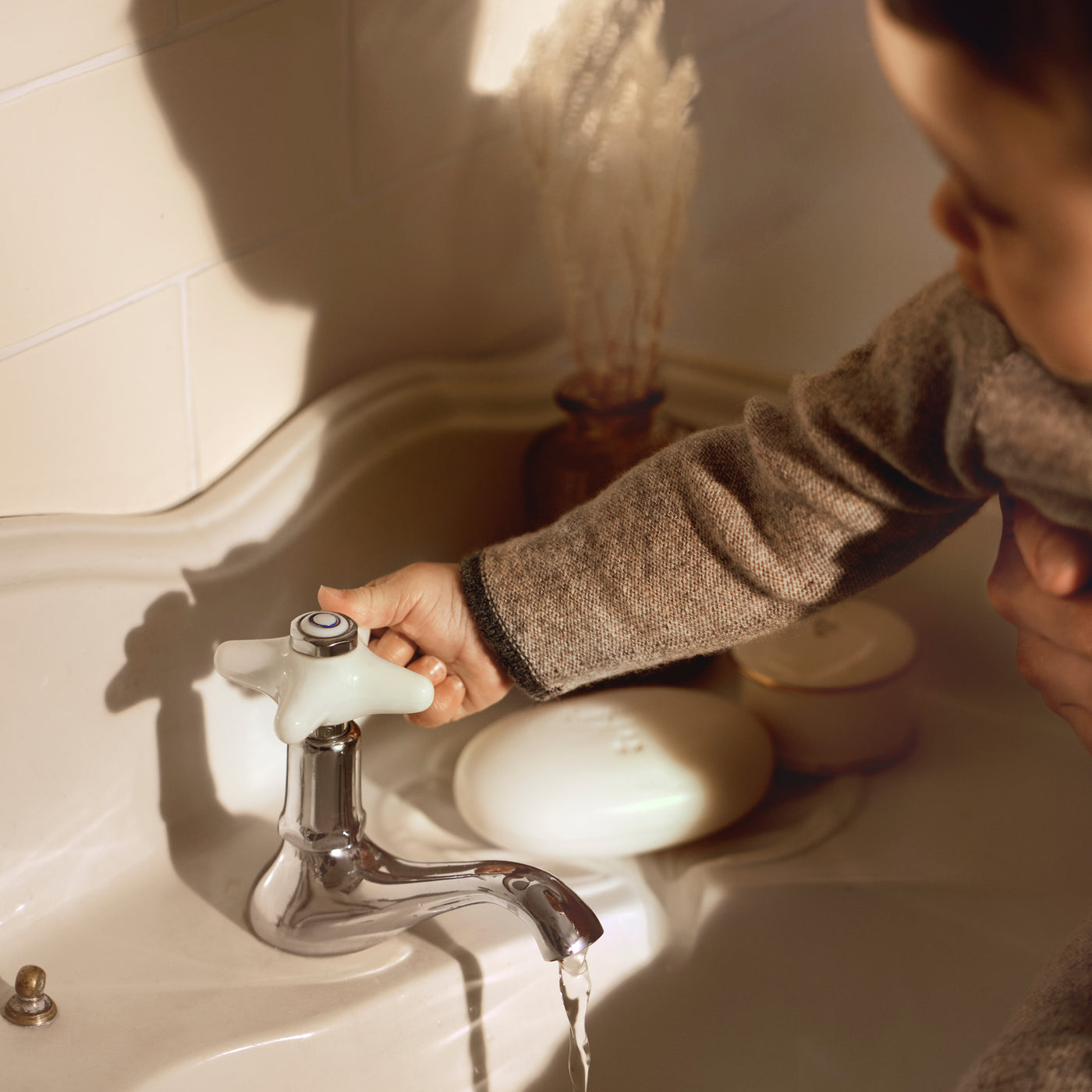 Bonpoint baby playing with faucet of sink