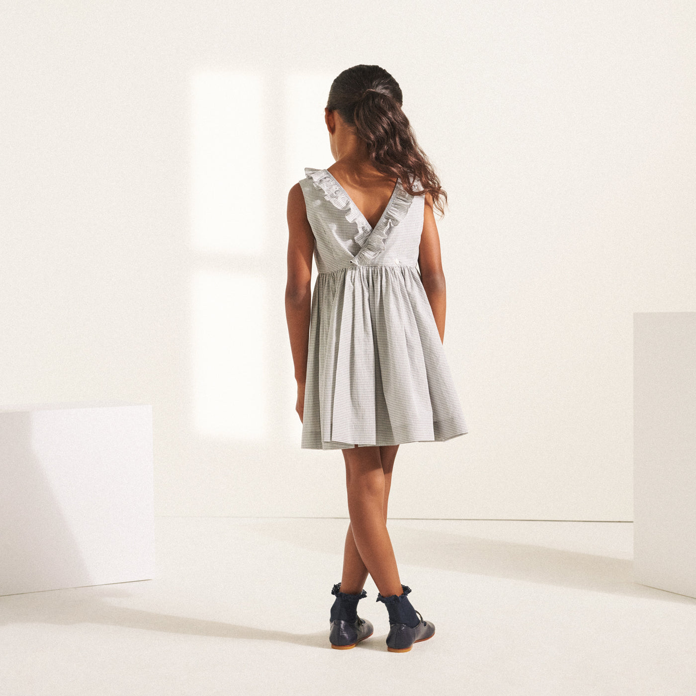 Back of girl in light grey dress with ruffle from Bonpoint Spring Summer 2022 Collection