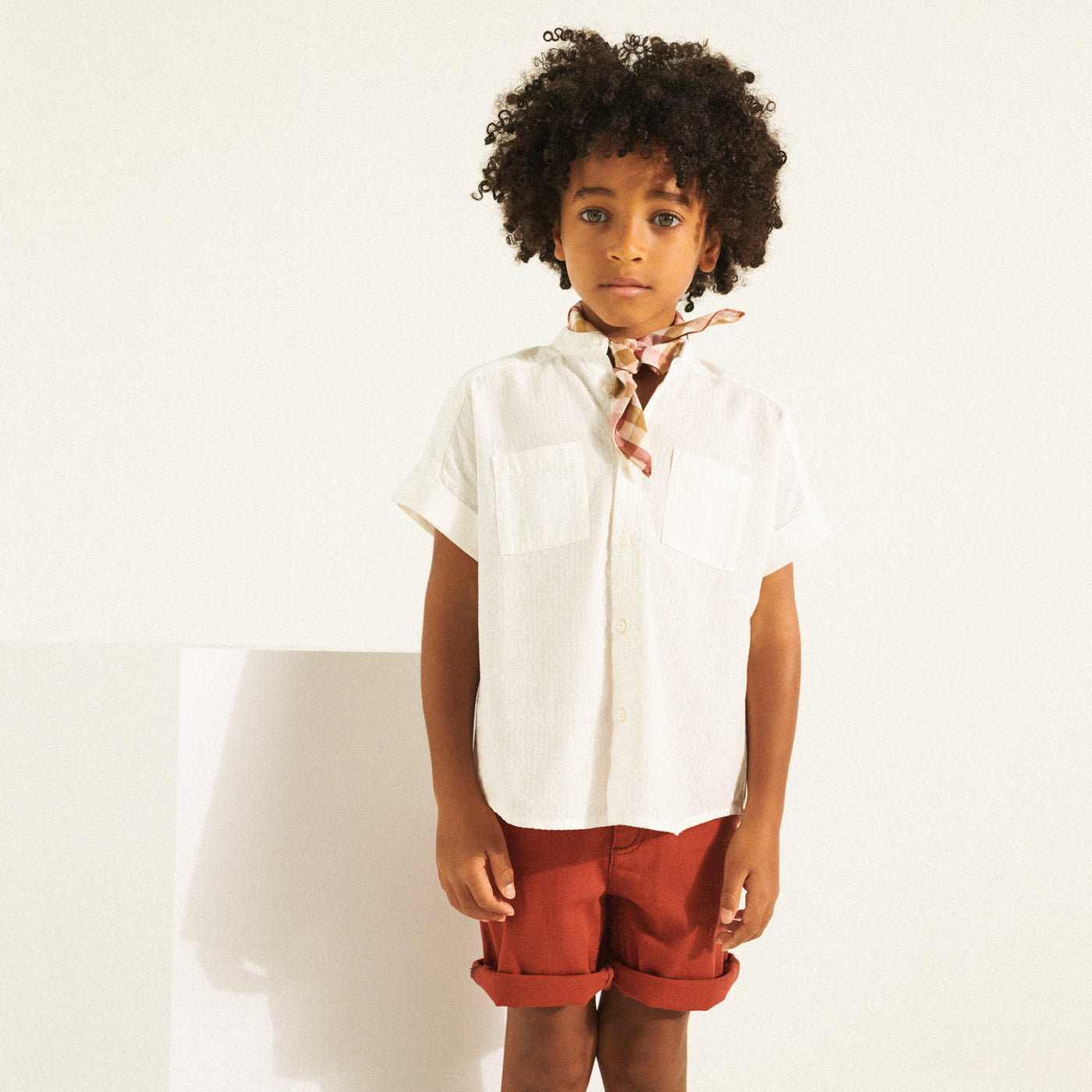 Boy in white shirt and little scarf around neck from Bonpoint Spring Summer 2022 Collection