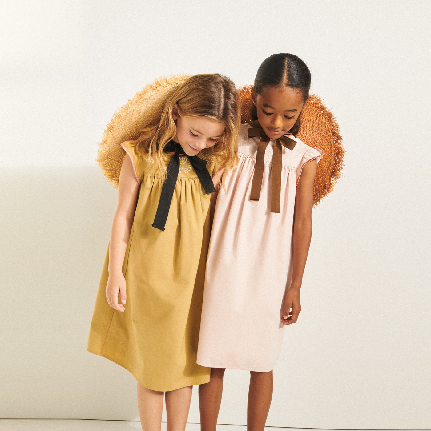Two girls in matching yellow and pink dresses from Bonpoint Spring Summer 2022 Collection