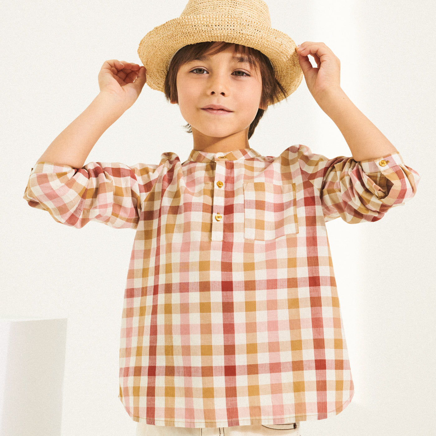Boy in pink and yellow checkered shirt with woven hat from Bonpoint Spring Summer 2022 Collection