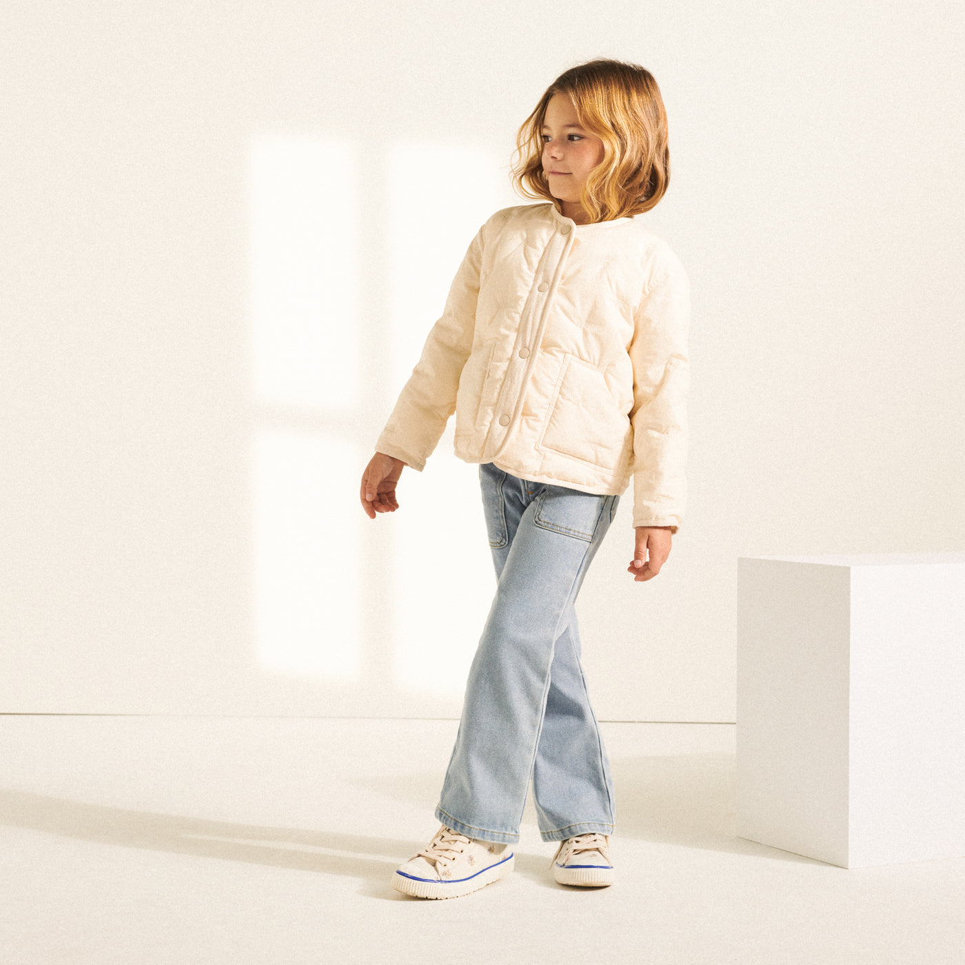 Girl in white jacket and light washed blue jeans from Bonpoint Spring Summer 2022 Collection