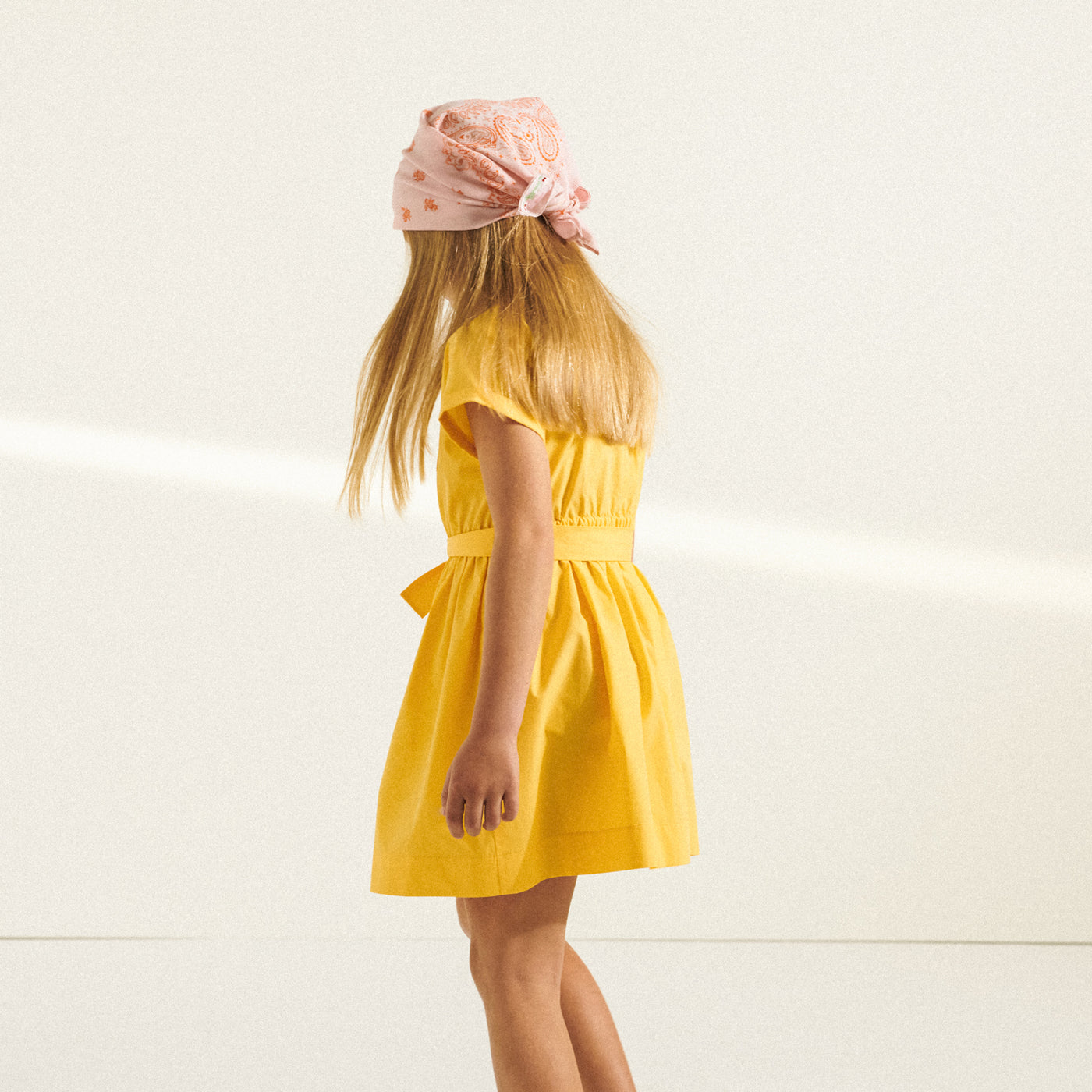Back of girl in yellow dress and pink bandana from Bonpoint Spring Summer 2022 Collection