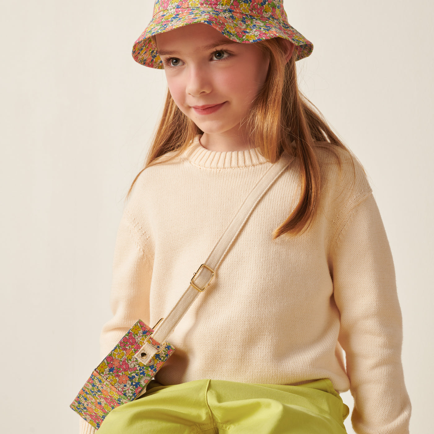 Girl in pale sweater with matching crossbody bag and bucket hat from Bonpoint Pre-Fall 2022 Collection
