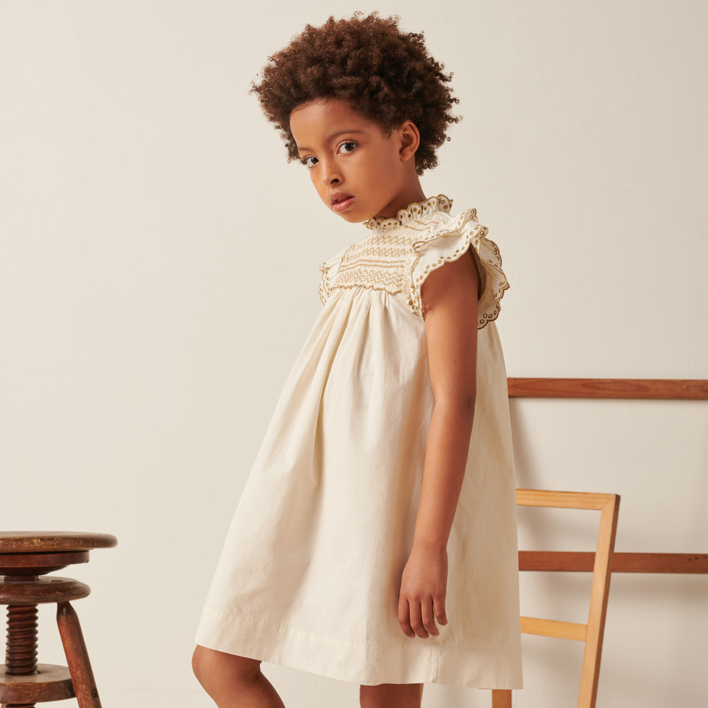Girl in cream dress with tan embroidery from Bonpoint Pre-Fall 2022 Collection