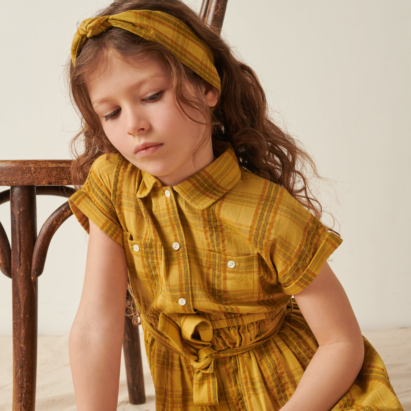 Girl wearing yellow plaid dress with matching headband from Bonpoint Pre-Fall 2022 Collection