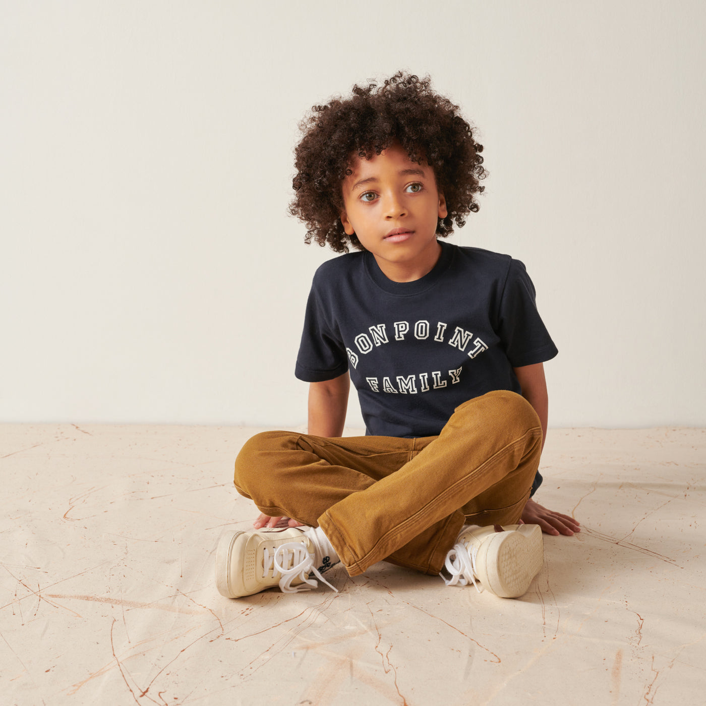 Boy sitting in navy blue Bonpoint family shirt from Bonpoint Pre-Fall 2022 Collection