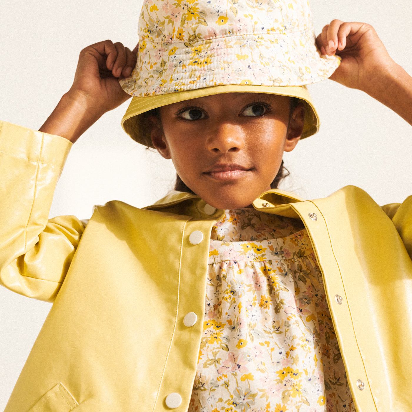 Girl in yellow floral shirt and yellow coat with matching bucket hat from Bonpoint Spring Summer 2022 Collection