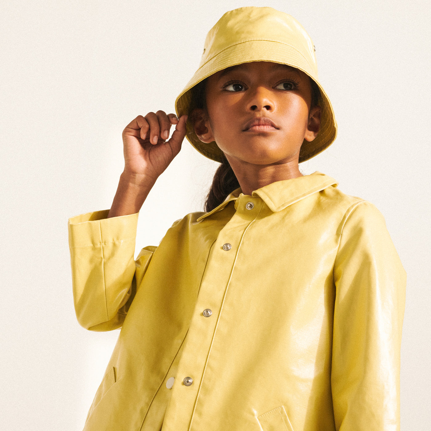 Girl in yellow raincoat with matching bucket hat from Bonpoint Spring Summer 2022 Collection