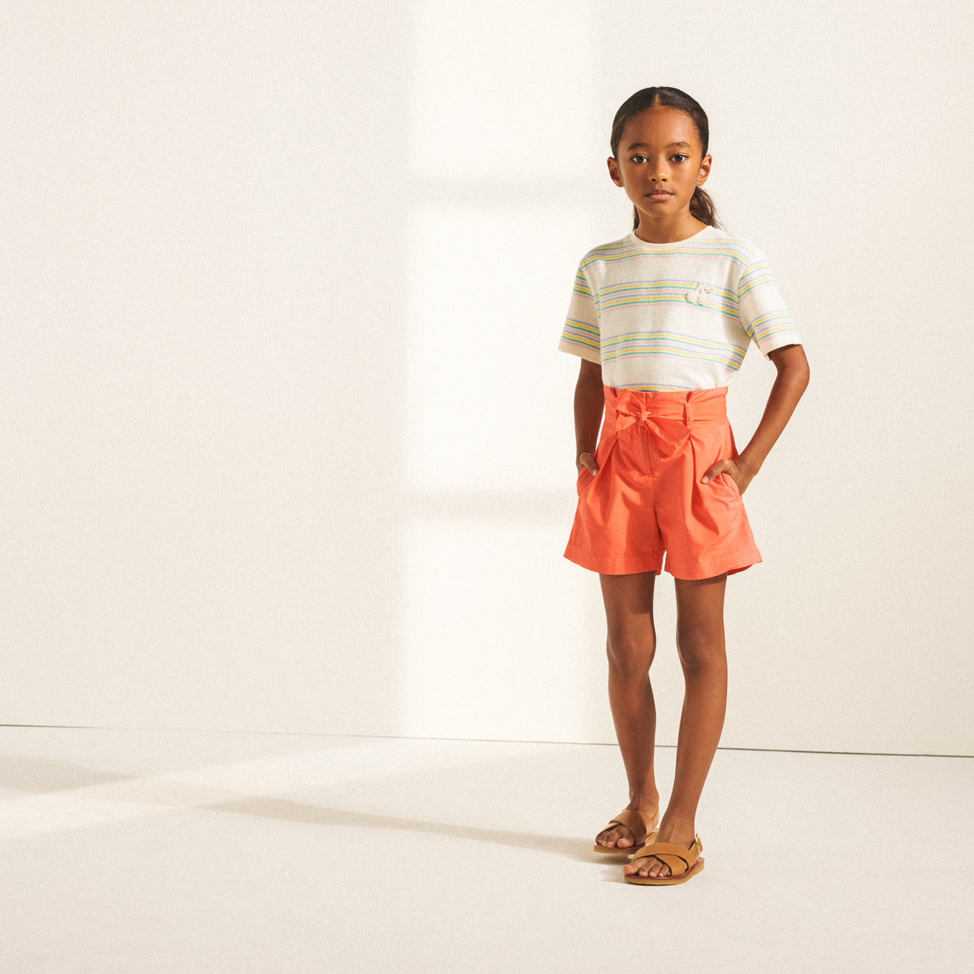 Girl in white shirt and coral shorts from Bonpoint Spring Summer 2022 Collection