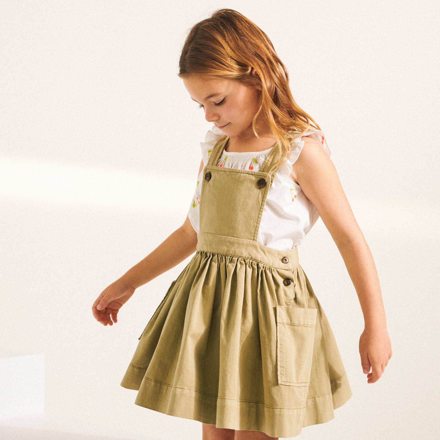 Girl in green toned overall dress from Bonpoint Spring Summer 2022 Collection