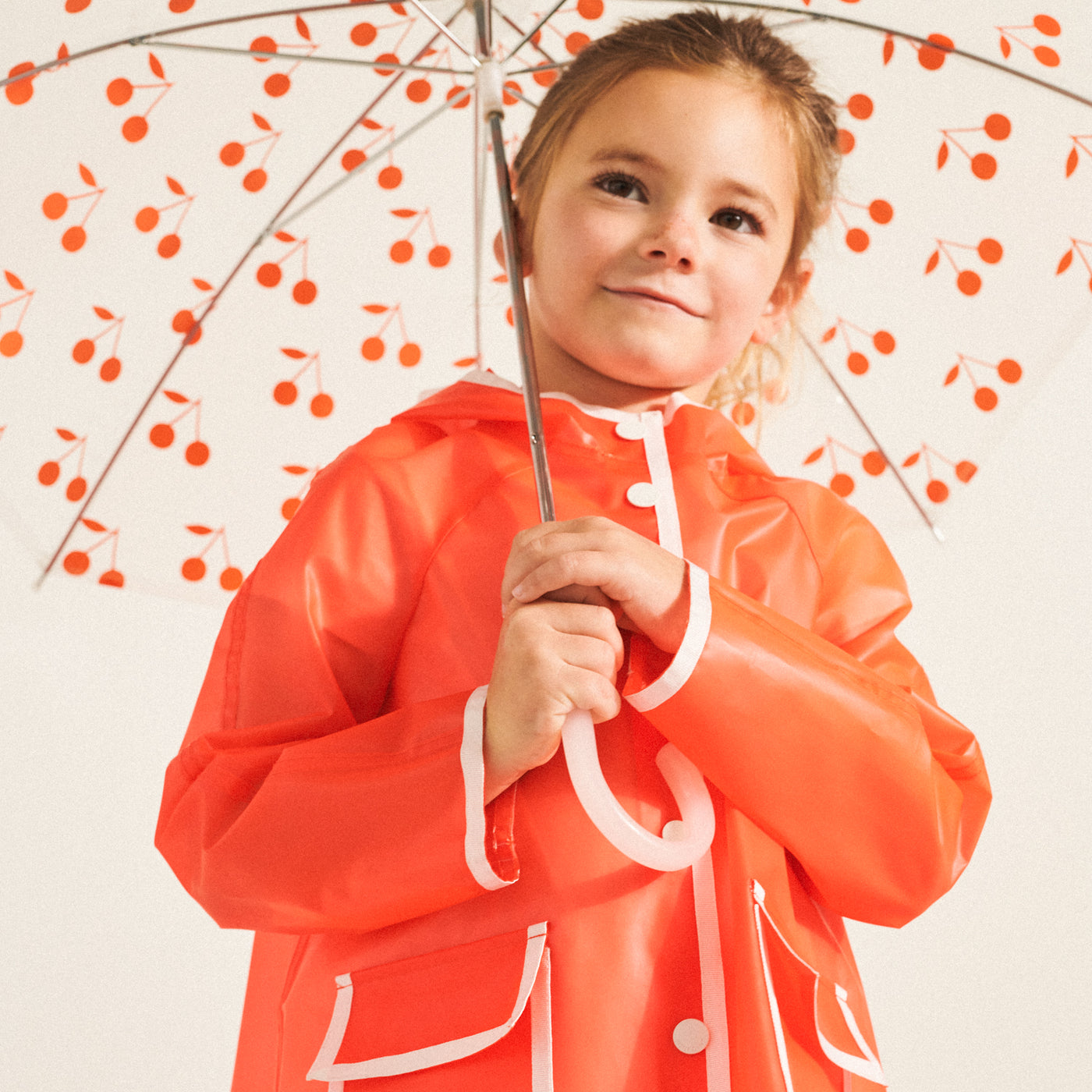 Girl in raincoat with cherry umbrella from Bonpoint Spring Summer 2022 Collection
