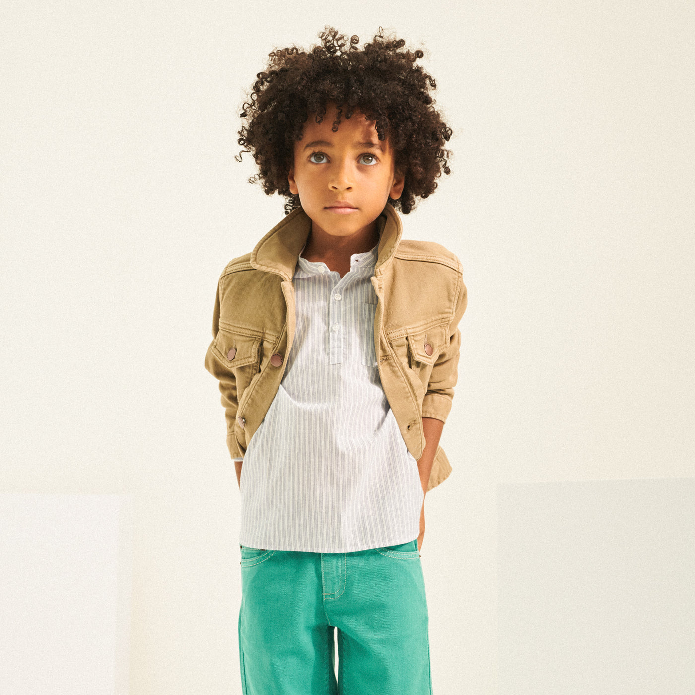 Boy in stripe shirt with tan jacket from Bonpoint Spring Summer 2022 Collection