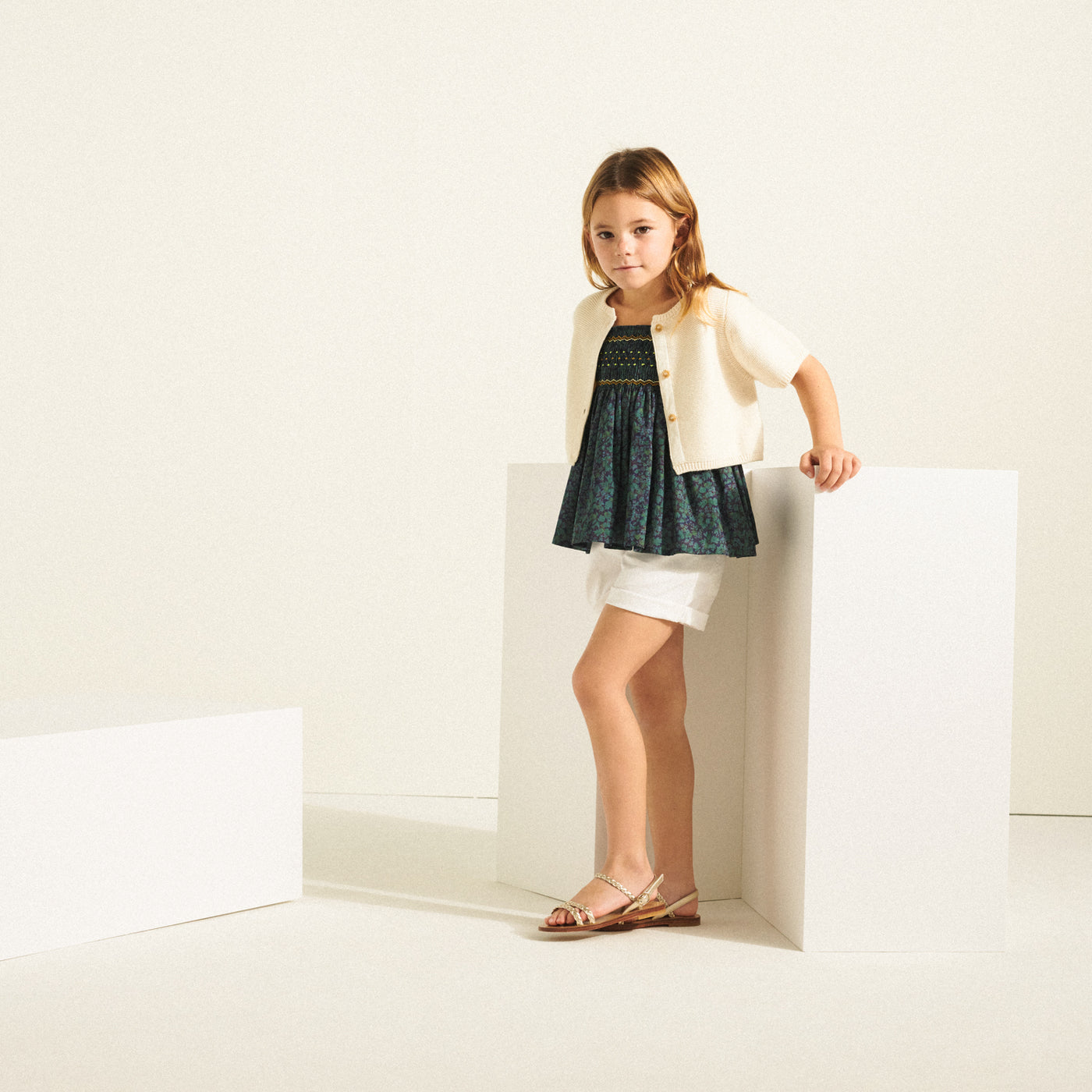 Girl posing in dark blouse with cream cardigan from Bonpoint Spring Summer 2022 Collection