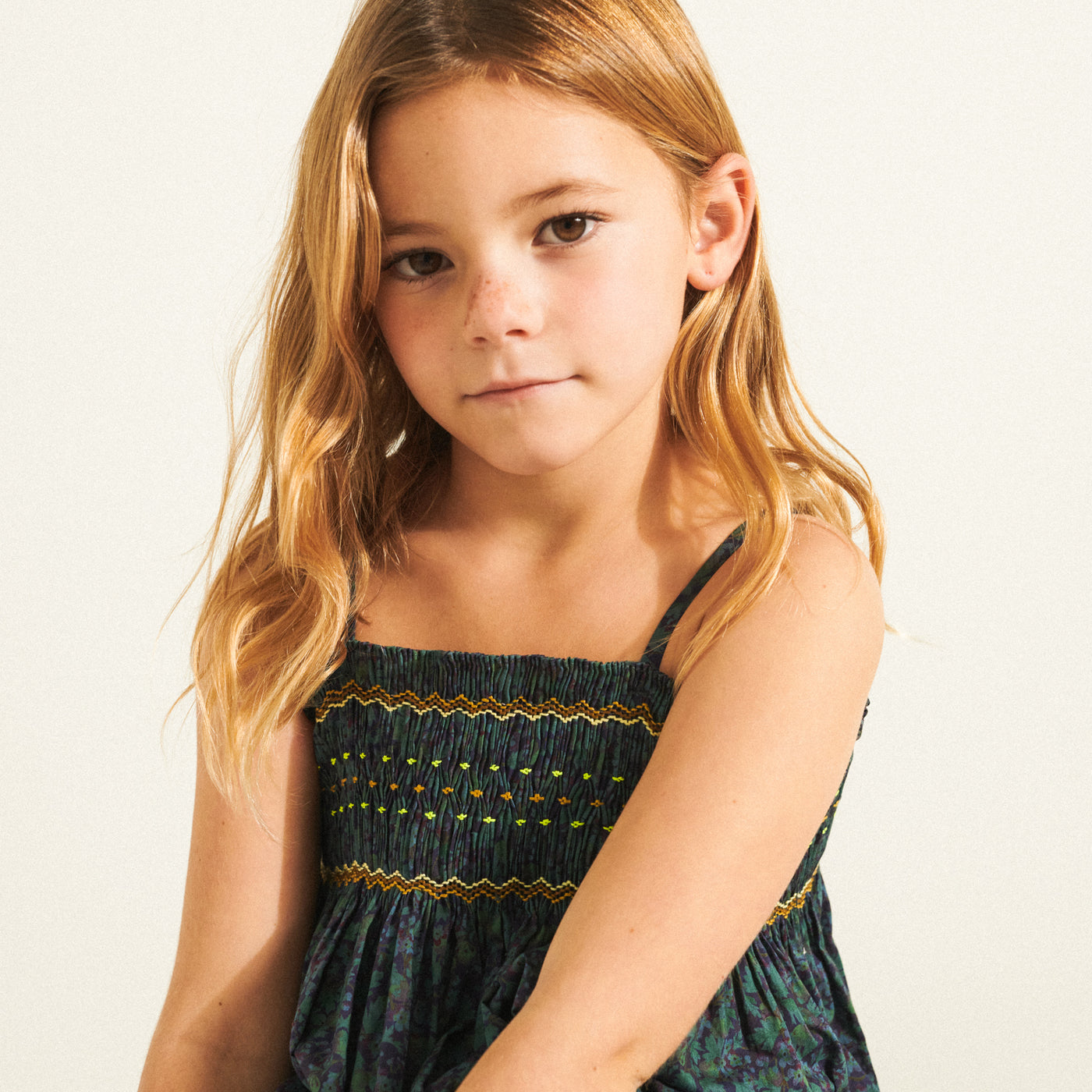 Girl in dark sleeveless blouse with embroidery from Bonpoint Spring Summer 2022 Collection