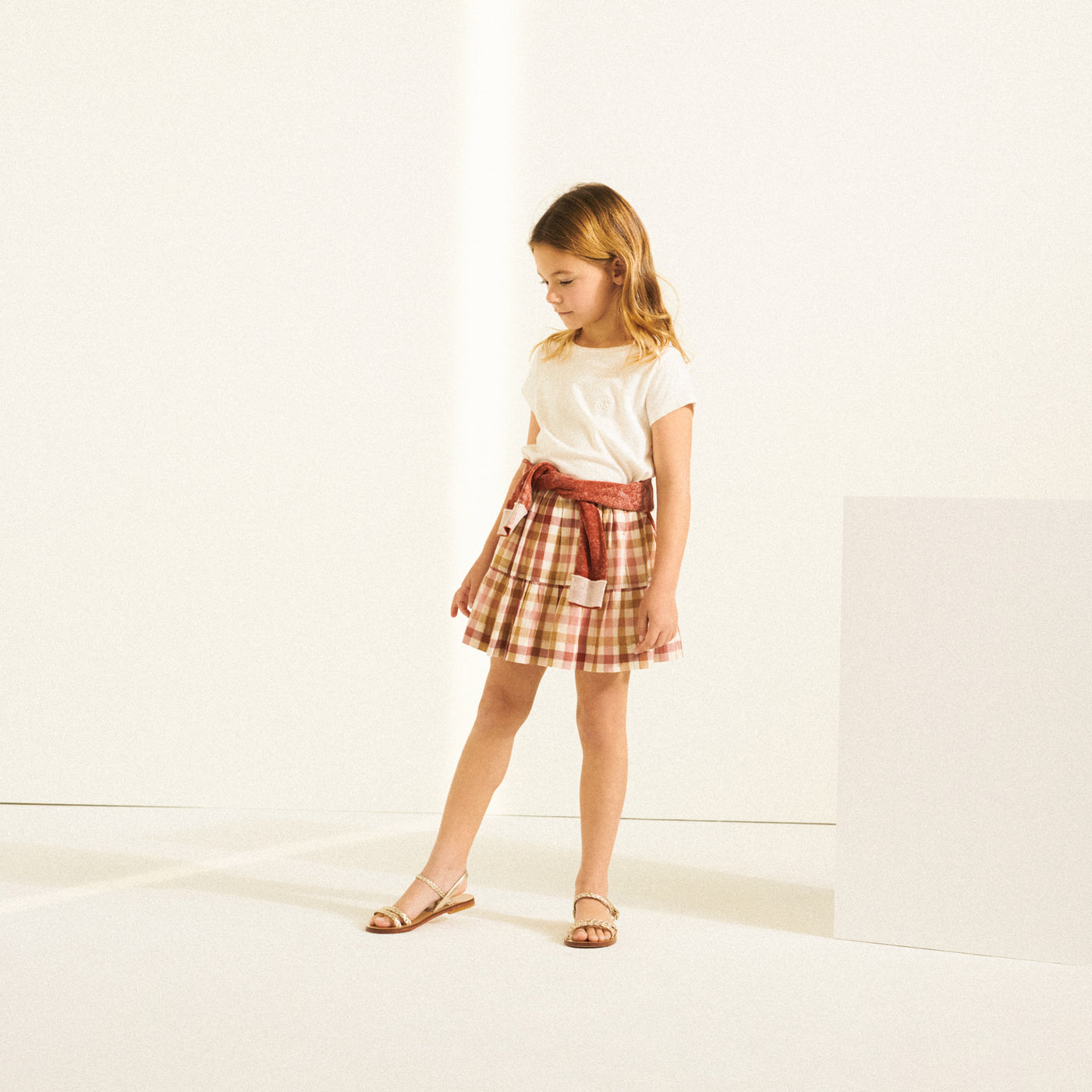 Girl in white t-shirt and printed skirt from Bonpoint Spring Summer 2022 Collection