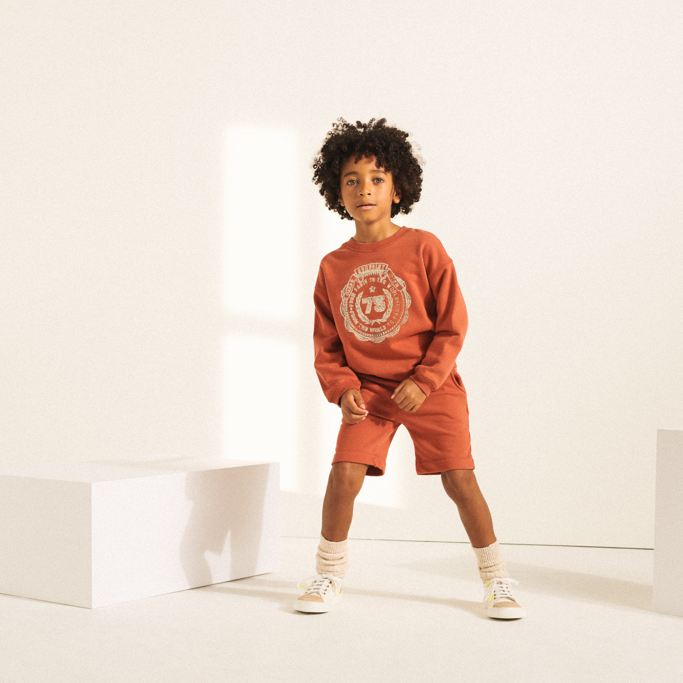Boy in matching orange sweat set from Bonpoint Spring Summer 2022 Collection