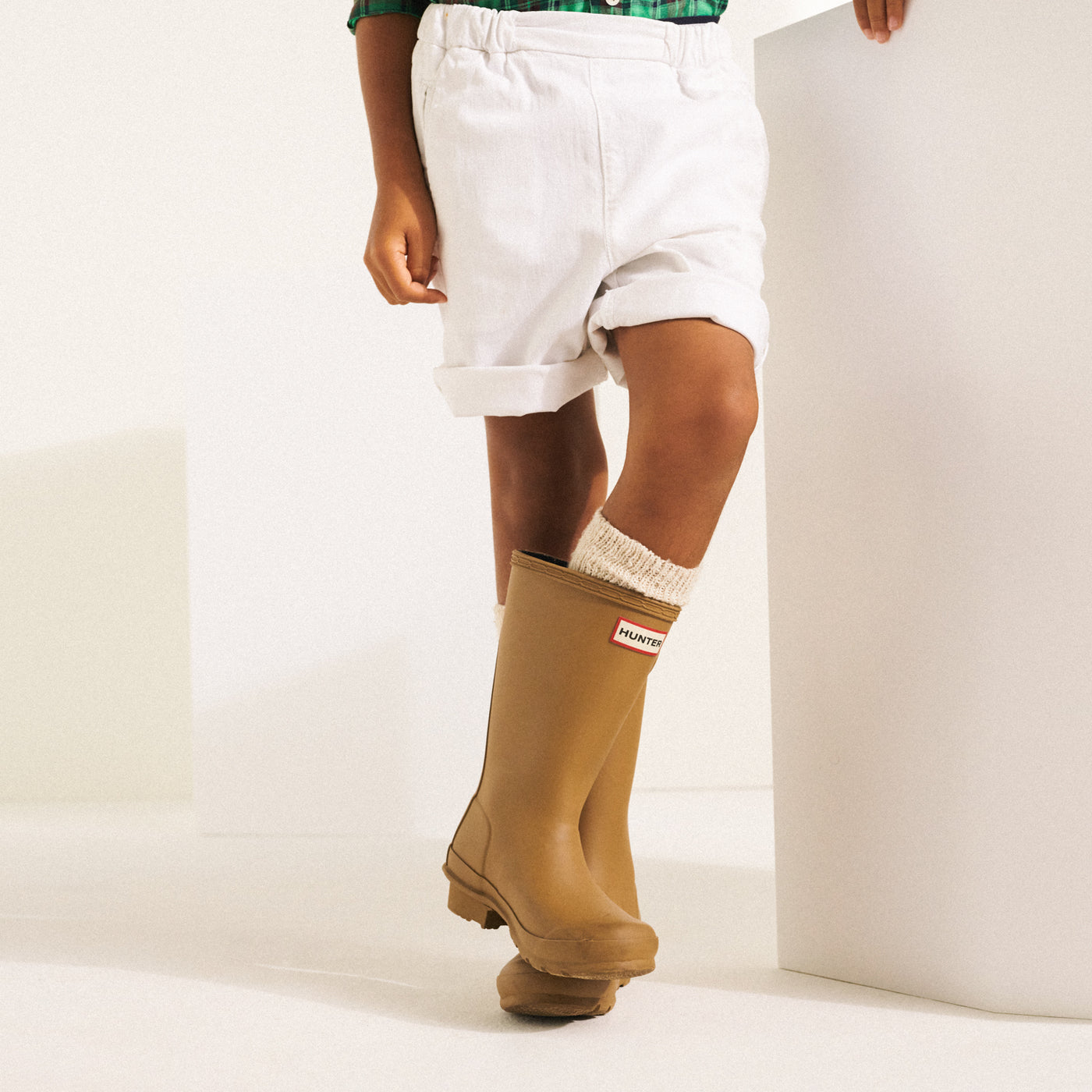 Child legs in white shorts with tan Hunter boots Bonpoint